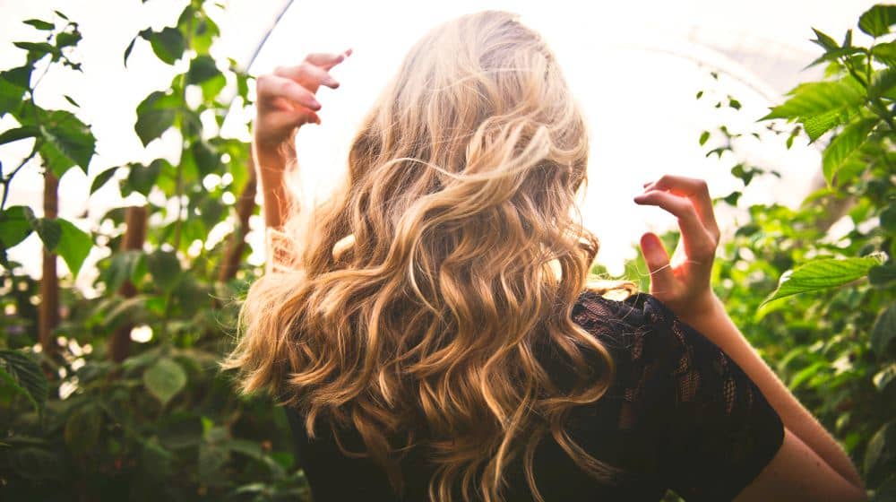 Woman with curled hair with green plants at the background